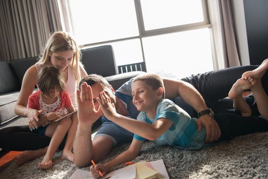 Happy Young Family Playing Together at home on the floor using a tablet and a children's drawing set