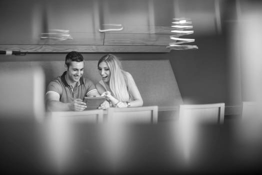 Young couple using tablet computer at luxury home together, looking at screen, smiling.