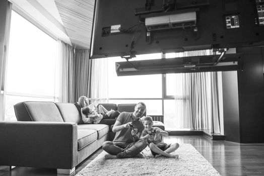 Happy family. Father, mother and children playing a video game Father and son playing video games together on the floor