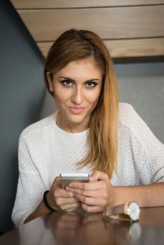 young happy woman sitting at the table and using mobile phone at luxury home