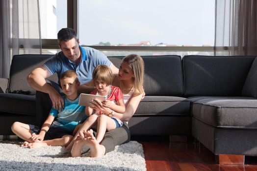 Happy Young Family Playing Together with tablet at home sitting on the sofa