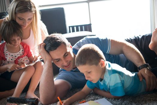 Happy Young Family Playing Together at home on the floor using a tablet and a children's drawing set