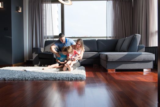 Happy Young Family Playing Together with tablet at home sitting on the sofa