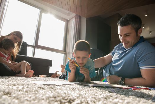 Happy Young Family Playing Together at home on the floor using a tablet and a children's drawing set