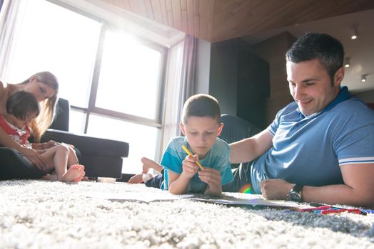 Happy Young Family Playing Together at home on the floor using a tablet and a children's drawing set