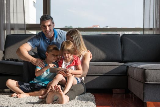 Happy Young Family Playing Together with tablet at home sitting on the sofa