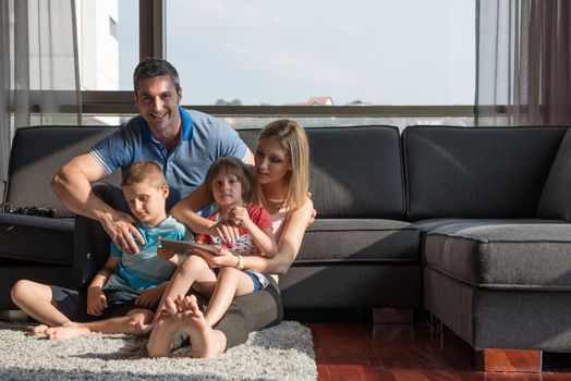 Happy Young Family Playing Together with tablet at home sitting on the sofa