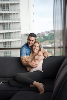 young handsome couple enjoys hugging on the sofa in their luxury home villa