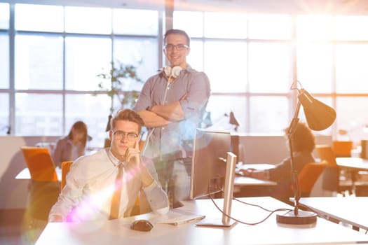 Young businessman helping his colleague to fix the problem at the work