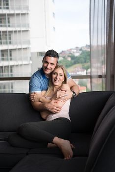 young handsome couple enjoys hugging on the sofa in their luxury home villa