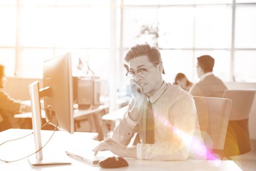 Young businessman programer in big bright office at work using computer