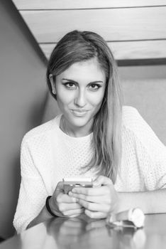 young happy woman sitting at the table and using mobile phone at luxury home