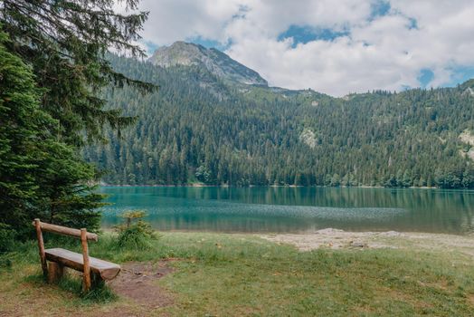 Relax. Rest near lake. Wooden bench overlooking the lake and mountains. Beautiful mystical lake. Black Lake, Durmitor National Park. Montenegro