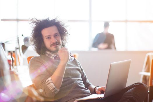 Young businessman programer in big bright office at work using computer