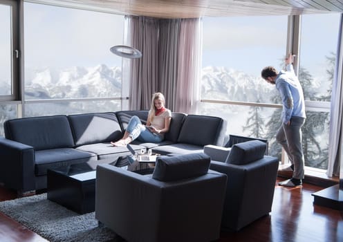 Young couple relaxing at  home using tablet computer reading in the living room near the window on the sofa couch.