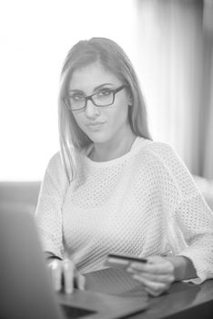 Young woman holding credit card and using laptop computer. Online shopping concept