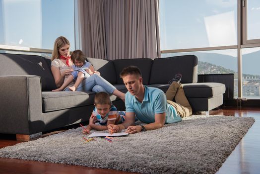 Happy Young Family Playing Together at home on the floor using a tablet and a children's drawing set