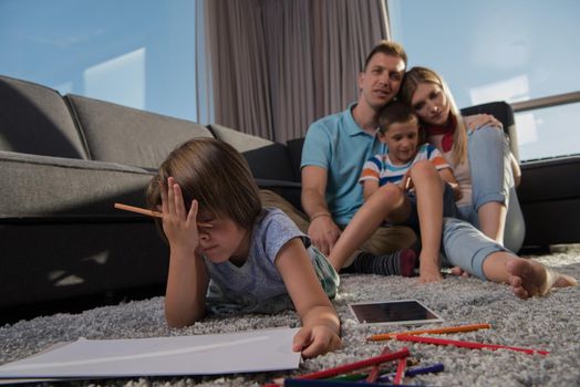 Happy Young Family Playing Together at home on the floor using a tablet and a children's drawing set