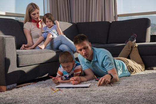 Happy Young Family Playing Together at home on the floor using a tablet and a children's drawing set