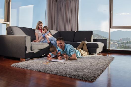 Happy Young Family Playing Together at home on the floor using a tablet and a children's drawing set