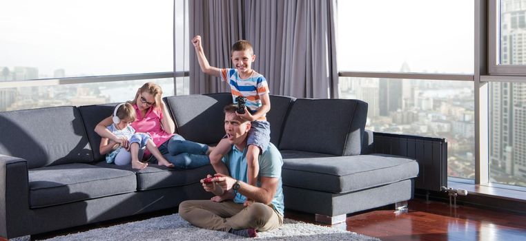 Happy family. Father, mother and children playing a video game Father and son playing video games together on the floor