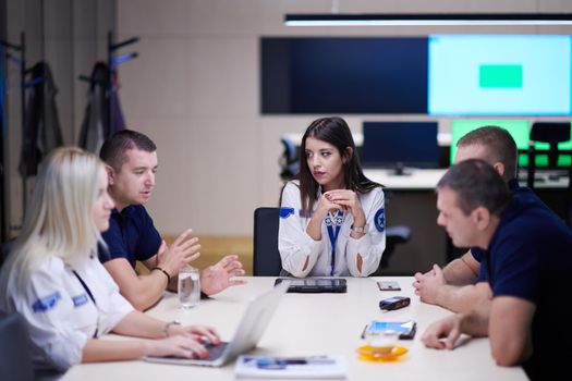 Group of security guards sitting and having briefing In the system control room  They're working in security data center surrounded by multiple Screens