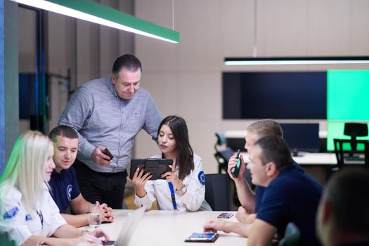 Group of security guards sitting and having briefing In the system control room  They're working in security data center surrounded by multiple Screens