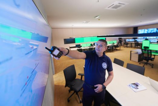 portrait of young male security operator working in a data system control room Working at workstation with multiple displays, security guard working on multiple monitors  Male computer operator monitoring from a security center