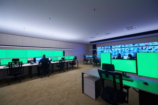 Group of Security data center operators working in a CCTV monitoring room looking on multiple monitors  Officers Monitoring Multiple Screens for Suspicious Activities  Team working on the System Control Room