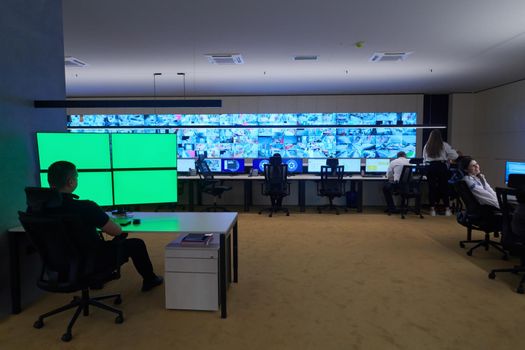 Group of Security data center operators working in a CCTV monitoring room looking on multiple monitors  Officers Monitoring Multiple Screens for Suspicious Activities  Team working on the System Control Room