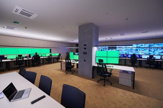 Group of Security data center operators working in a CCTV monitoring room looking on multiple monitors  Officers Monitoring Multiple Screens for Suspicious Activities  Team working on the System Control Room