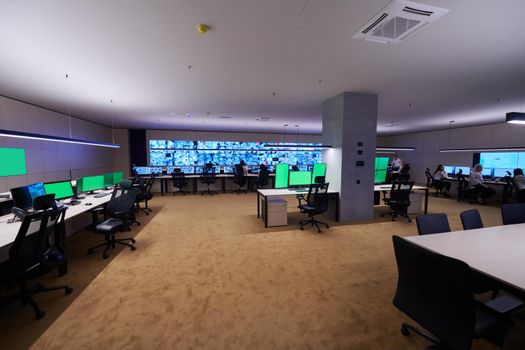 Group of Security data center operators working in a CCTV monitoring room looking on multiple monitors  Officers Monitoring Multiple Screens for Suspicious Activities  Team working on the System Control Room