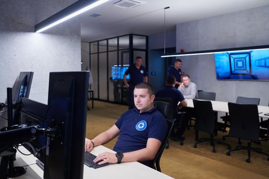 Group of Security data center operators working in a CCTV monitoring room looking on multiple monitors  Officers Monitoring Multiple Screens for Suspicious Activities  Team working on the System Control Room
