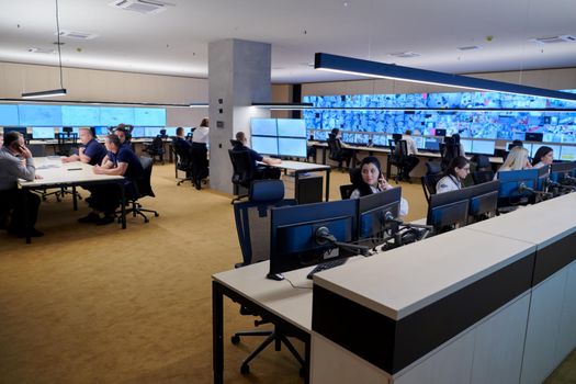 Group of Security data center operators working in a CCTV monitoring room looking on multiple monitors  Officers Monitoring Multiple Screens for Suspicious Activities  Team working on the System Control Room