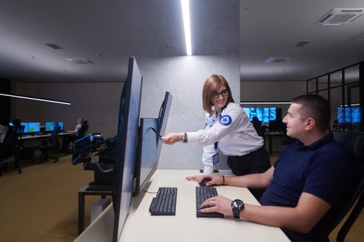 Group of Security data center operators working in a CCTV monitoring room looking on multiple monitors  Officers Monitoring Multiple Screens for Suspicious Activities  Team working on the System Control Room