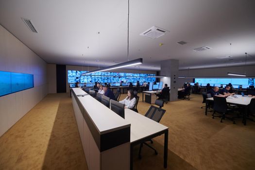 Group of Security data center operators working in a CCTV monitoring room looking on multiple monitors  Officers Monitoring Multiple Screens for Suspicious Activities  Team working on the System Control Room