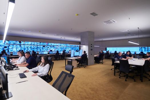 Group of Security data center operators working in a CCTV monitoring room looking on multiple monitors  Officers Monitoring Multiple Screens for Suspicious Activities  Team working on the System Control Room