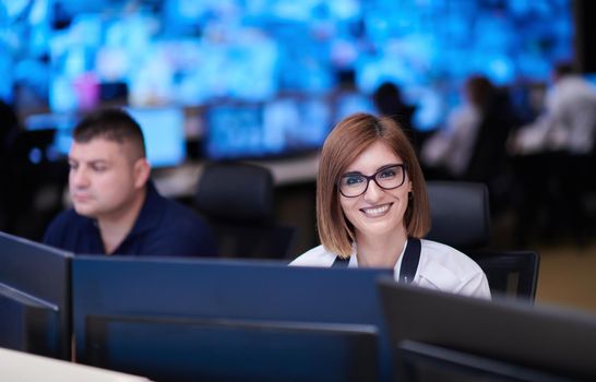 Female security operator working in a data system control room offices Technical Operator Working at  workstation with multiple displays, security guard working on multiple monitors