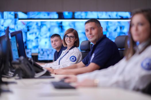 Group of Security data center operators working in a CCTV monitoring room looking on multiple monitors  Officers Monitoring Multiple Screens for Suspicious Activities  Team working on the System Control Room