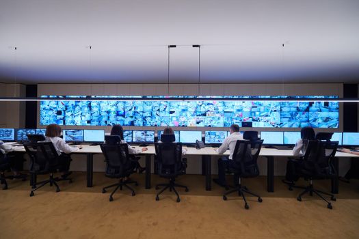 Group of Security data center operators working in a CCTV monitoring room looking on multiple monitors  Officers Monitoring Multiple Screens for Suspicious Activities  Team working on the System Control Room