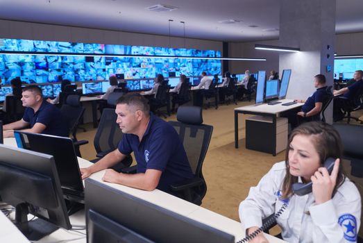 Group of Security data center operators working in a CCTV monitoring room looking on multiple monitors  Officers Monitoring Multiple Screens for Suspicious Activities  Team working on the System Control Room