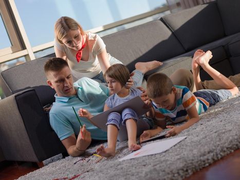 Happy Young Family Playing Together at home using a tablet and a children's drawing set