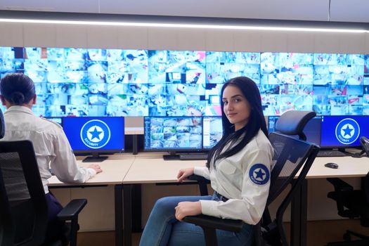 portrait of female security operator while working in a data system control room offices Technical Operator Working at  workstation with multiple displays, security guard working on multiple monitors