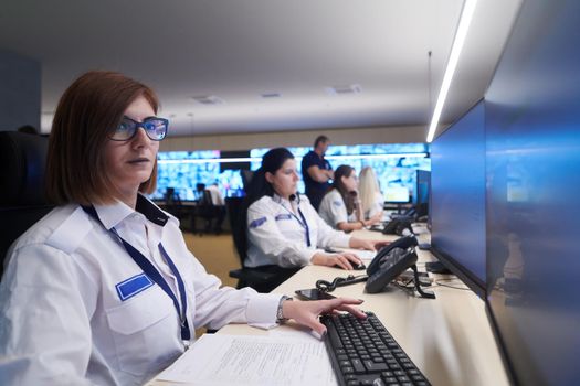 Group of Security data center operators working in a CCTV monitoring room looking on multiple monitors  Officers Monitoring Multiple Screens for Suspicious Activities  Team working on the System Control Room