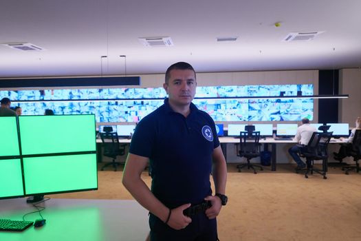 portrait of young male security operator working in a data system control room Working at workstation with multiple displays, security guard working on multiple monitors  Male computer operator monitoring from a security center