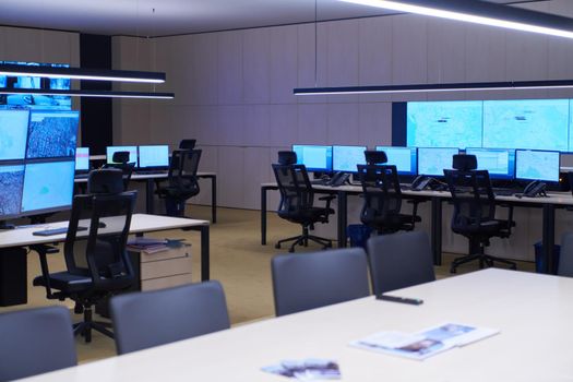 Empty interior of big modern security system control room, workstation with multiple displays, monitoring room with at security data center  Empty office, desk, and chairs at a main CCTV security data center