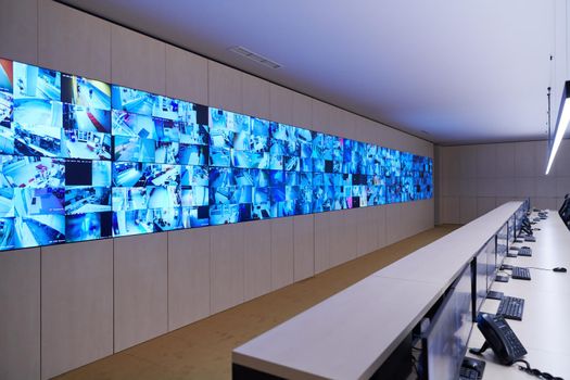 Empty interior of big modern security system control room, workstation with multiple displays, monitoring room with at security data center  Empty office, desk, and chairs at a main CCTV security data center