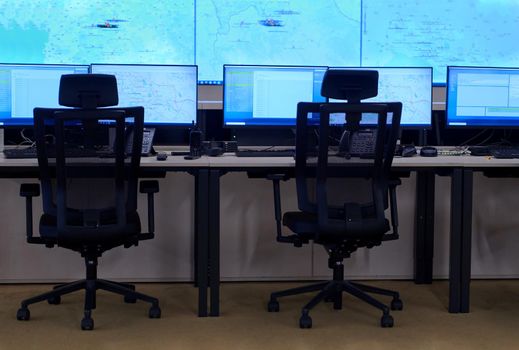 Empty interior of big modern security system control room, workstation with multiple displays, monitoring room with at security data center  Empty office, desk, and chairs at a main CCTV security data center