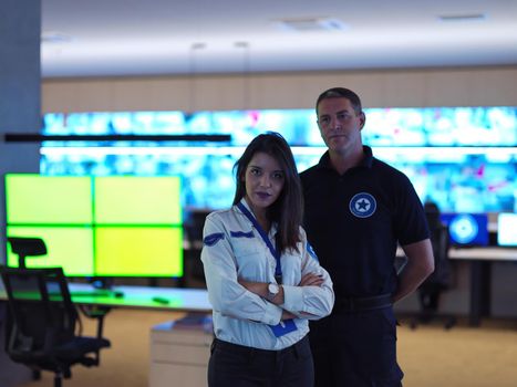 portrait of male and female security operator while working in a data system control room offices Technical Operator Working at  workstation with multiple displays, security guard working on multiple monitors
