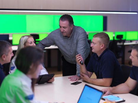 Group of security guards sitting and having briefing In the system control room  They're working in security data center surrounded by multiple Screens